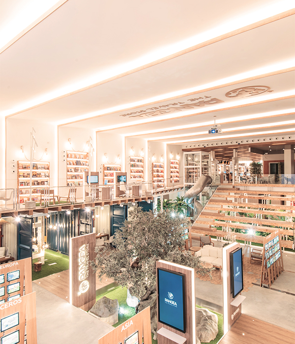 Imagen donde se ve la tienda de PANGEA Barcelona con la pantalla de cine al fondo y los puestos para diseñar un viaje en los laterales